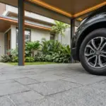 Perbandingan lantai carport batu alam andesit kuat anti-slip vs keramik granit di rumah tropis Indonesia.
